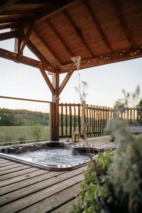 Jacuzzi bouillonnant sous une pergola avec guirlande lumineuse