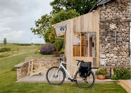Vélo de voyage devant une maisonnette en pierre