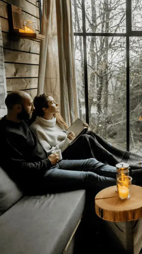 Couple détendu sur un canapé devant une baie vitrée