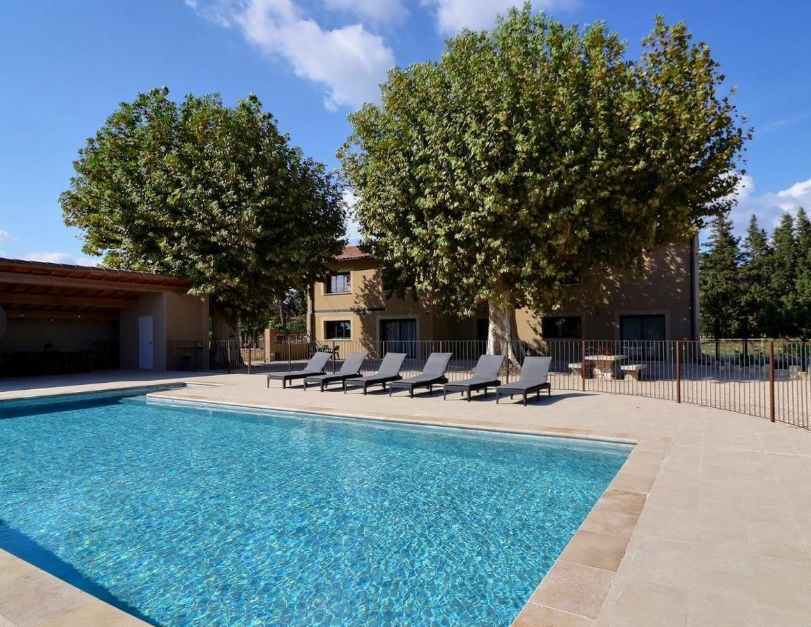 Piscine entourée par une terrasse avec bains de soleil
