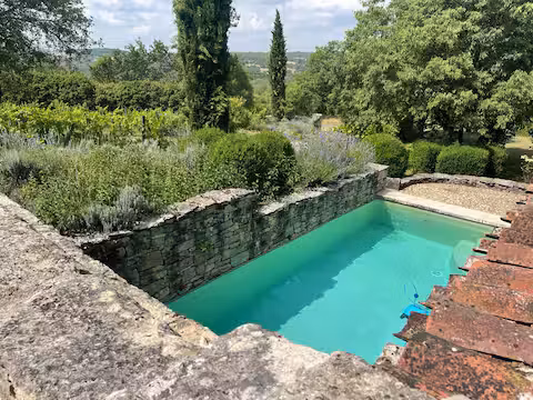 Piscine de la Grange avec vue sur le lointain dans les Causses et sur les différents corps de bâtiments du Domaine, et la piscine intimiste nichée dans les murs de pierres sèches et de verdure