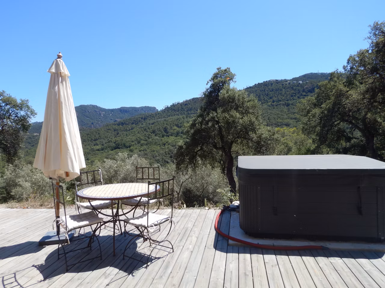 Grande terrasse en bois où un jacuzzi et des bains de soleil vous attendent pour vous détendre.